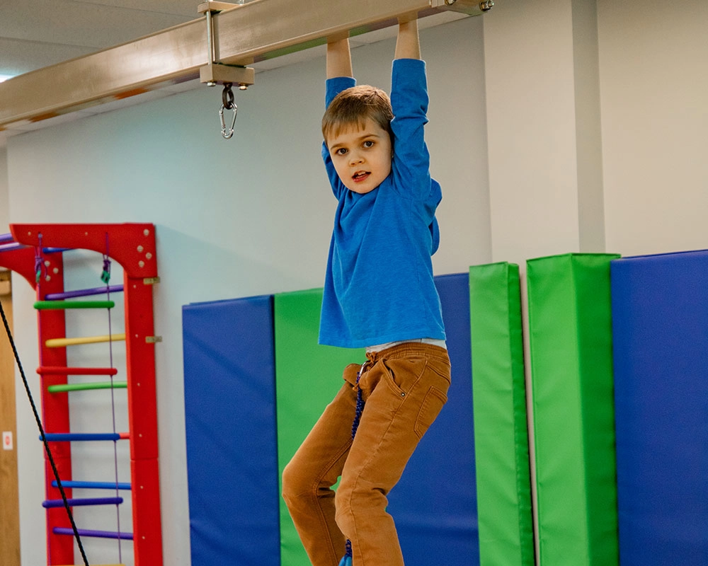 My oldest son, Grant, hanging from the industrial swings at the Superhero Center for Autism